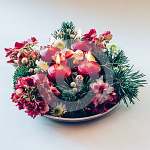 four red advent candles on round wreath, 4 candles burning