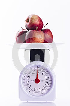 Four red apples on weighing scales