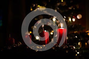 Four red candles - the first lighted candle of the first Sunday of Advent festival before Christmas with tree and decoration in ba