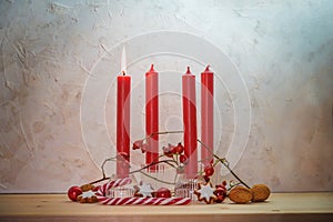 Four red candles, one is lit for the first Sunday before Christmas, Advent decoration on a wooden table against a rustic wall,