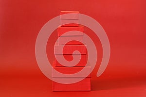 Four red cardboard boxes of different sizes on a red background. Minimalism