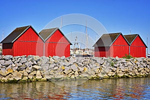 Four red fisher houses behind the stone groyne at the harbor Weisse Wiek in Boltenhagen at the Baltic Sea. Germany