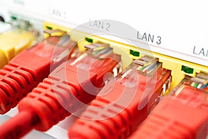 Four red patch cords are inserted in a white router. Internet connection