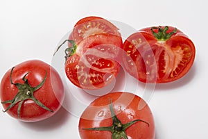 Four red tomatoes whole half cut on white background close