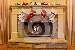 Four red and white Christmas stockings adorn a stone fireplace.