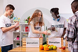 Four responsible teenagers putting food into boxes for donation