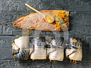 Four rolls of mackerel with vegetables, a bowl of vegetables and sliced fish carcass on a wooden table. The view from the top. Fla