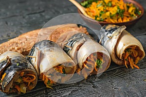 Four rolls of mackerel with vegetables on a wooden rustic table.