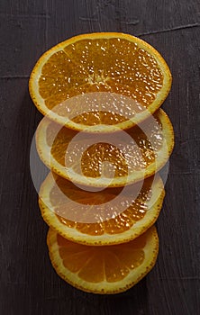 Four round slices of ripe and juicy orange close-up on a black background