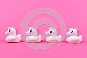 Four rubber duck unicorn in a row on pink background