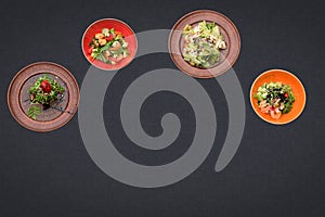 Four salads on a black background lie in a semicircle with sopy space