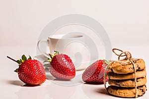 Four sand biscuits with black chocolate bandaged with canvas rope, are on a shiny white plastic background.Nearby with a