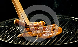 Four sausages cooking on a portable barbecue photo