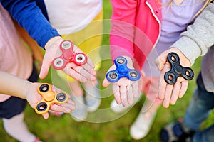 Four school children playing with fidget spinners on the playground. Popular stress-relieving toy for school kids and adults.