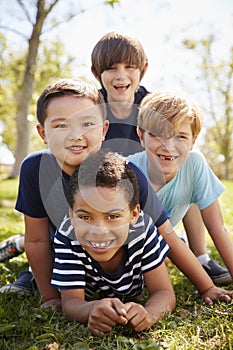 Four schoolboys lying on each other in a park, portrait