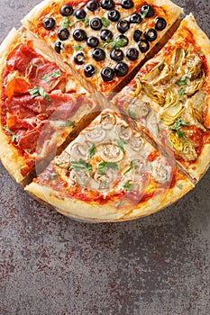 Four seasons pizza quattro stagioni made with tomato sauce, mozzarella cheese, ham, artichokes, olives and mushrooms closeup on