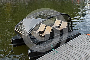 Four-seater electric catamaran at the wooden pier. Compact pontoon boat renting