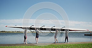 Four senior caucasian men and women carrying a rowing boat together