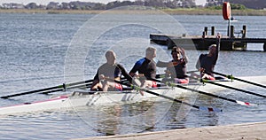 Four senior caucasian men and women in rowing boat raising hands and cheering