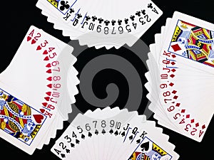 Four sets of poker playing cards with black background.