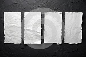 Four sheets of white torn paper on a black wall