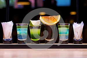 Four shots with alcoholic cocktails on a wooden plank