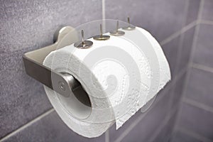 Four silver big thumbtacks or drawing-pins on toilet paper