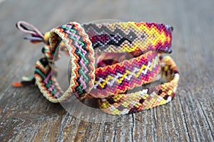 Four simple handmade homemade natural woven bracelets of friendship on wooden background, rainbow colors