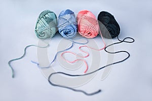 Four skeins of yarn with loosened threads on grey background