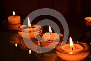 Four small candlesticks with burning even flame candles on a smooth surface