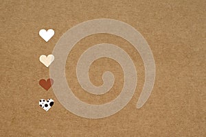 four small hearts on brown craft paper background