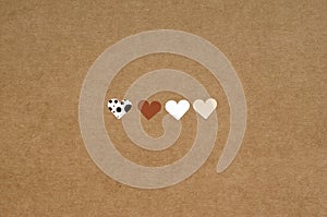 four small hearts on brown craft paper background