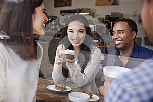 Four smiling friends having coffee at coffee shop, close up