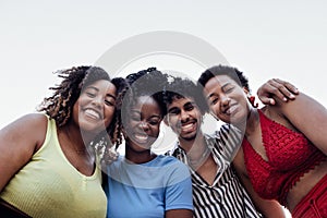 Four smiling mixed race friends standing and looking down at camera. Group of cheerful multiethnic people in casual clothes having