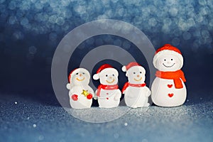 Four snowman figures on a shiny paper background. Christmas decorative smiling snowmen. Horizontal banner. Copy Space