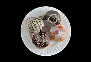 Four special sufganiyot with different icing on a white plate