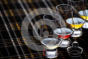 Four Special tulip-shaped glasses for tasting of Scotch whisky on distillery in Scotland, UK and dark tartan