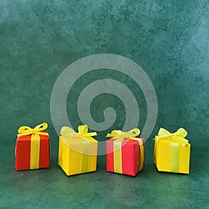 Four square red and yellow gift boxes on green textured background, Four in a row , square.