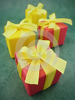 Four square red and yellow gift boxes on green textured background. vertical.
