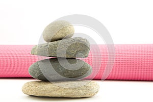 Four stacked river rocks with pink yoga mat
