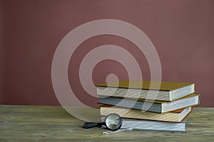 Four stamp albums books bunch, loupe and tweezers on wooden table and bordeaux background