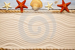 Four starfish and shell on wooden plank, hawser and beach sand photo