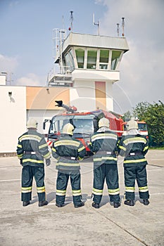 Four strong men standing in front of fire modern truck