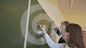 Four students write on the blackboard mathematical formulas in the classroom. Russian school.