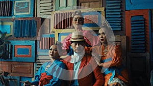 Four stylish models posing in front of a colorful wooden pallet background, showcasing eclectic fashion