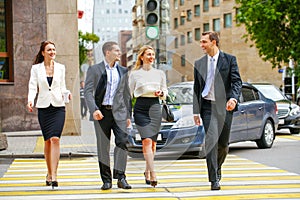 Four successful business people crossing the street in the city