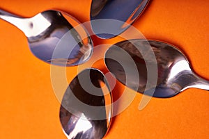 Four teaspoons laid out on an orange background
