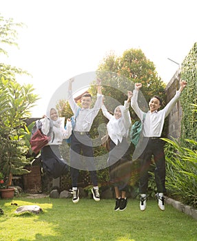 four teenagers hopping cheerfully in junior high school uniforms at the graduation announcement