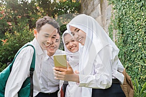 four teenagers in junior high school uniforms using and looking at cellphones