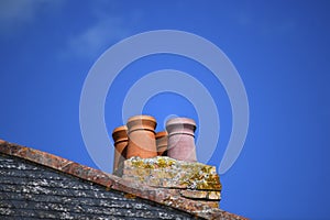 Four terracotta roof chimneys with clear blue sky